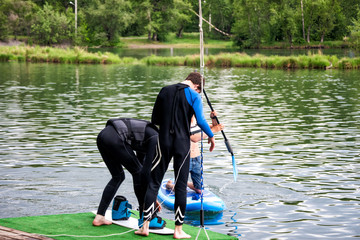 Man wakeboarding with coach on river lake sea on summer spring day in jacket