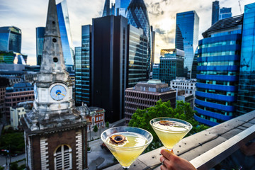 Fruit cocktails on the foreground and blurry aerial view of skyscrapers of the world famous bank district of central London at sunset - Powered by Adobe