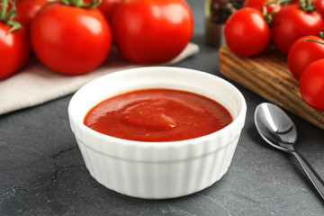 Composition with bowl of tomato sauce on grey table