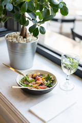 Fresh raw vegetarian salad of spinach leaves with quinoa and chia seeds. Juicy grapefruit, red pomegranate and sweet pomelo. In a deep plate with golden cutlery. Glass water, breakfast.