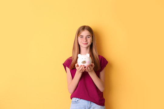 Teen Girl With Piggy Bank On Color Background