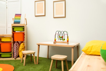 Stylish playroom interior with table and stools