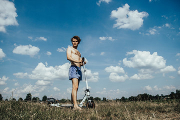 Young male on the beach an electric scooter driver on a sunny day.