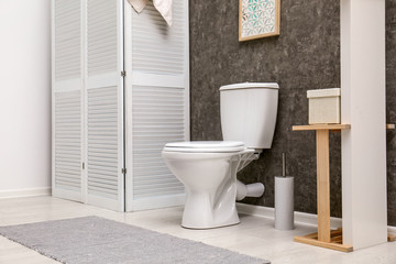 Toilet bowl near dark wall in modern bathroom interior