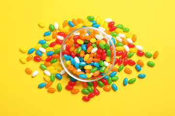 Bowl of jelly beans on color background, top view