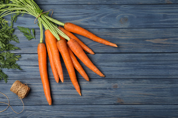 Flat lay composition with carrots on wooden background. Space for text