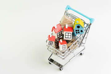 Buy and sell house, property demand and supply on real estate purchasing concept, shopping cart or trolley with full of small cute miniature houses on white background