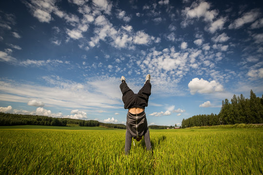 Handstand in green field on beautiful sunshine day with blue sky