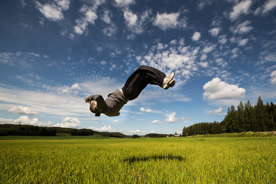 Backflip in green field on beautiful sunshine day with blue sky