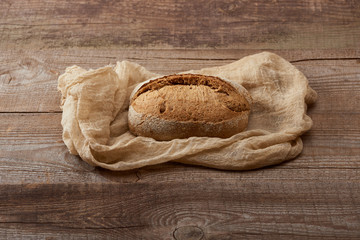 fresh baked bread loaf on cloth on wooden table
