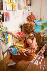 Stylish talented artist feeling amazing while painting on canvas