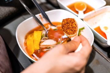 Close up of hand adding more spicy chilli powder in noodle. Thai local food menu.