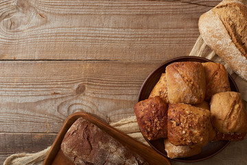 top view of bread loaves and buns on rustic cloth on wooden table