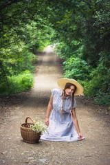 Obraz premium Girl in blue floral with yellow hat dress sitting in the middle of the road