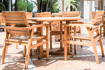 Fototapeta na wymiar Set of wooden chairs and circular table in outdoor cafe at hotel area.