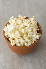 Ceramic bowl with popcorn on gray background