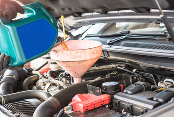 Close up of car mechanic hand filling new oil into engine at repair service station.