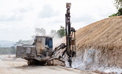 Rock driller on road comnstruction. Drilling rock in the works of creating a road.