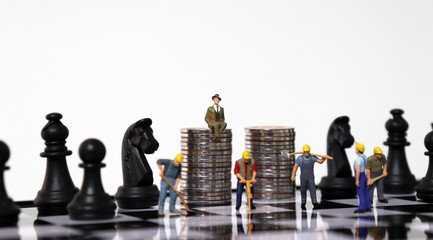 Pile of coins and miniature people on the chessboard.