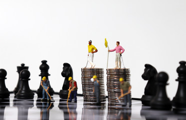 Pile of coins and miniature people on the chessboard. The concept of inequality between labor and...