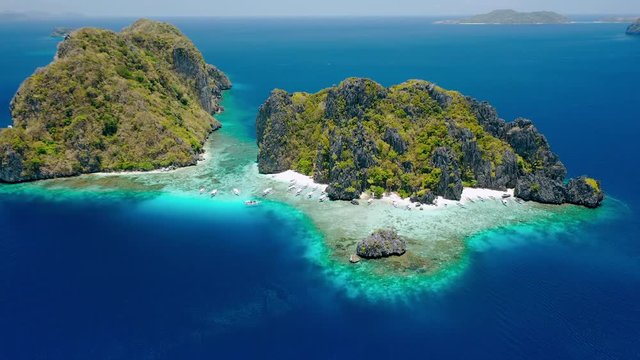 Aerial drone footage of Shimizu Island from distance in El Nido, Palawan, Philippines. Rocks and crystal clear turquoise lagoon water in front of the island
