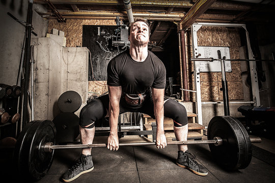 Young man weight training in a gritty basement gym.