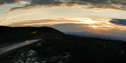 Traveling down a darkening country highway as the sun sets behind him.
