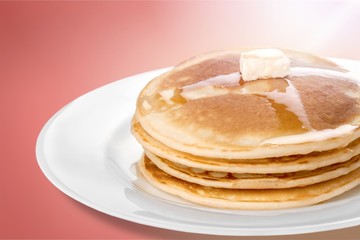 Stack of tasty pancakes with butter on a white plate