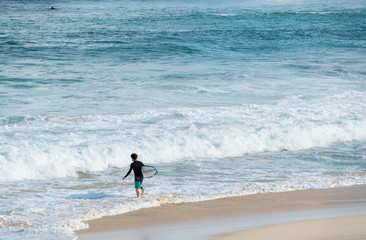 A surfer getting ready for the surf, going surfing in ocean