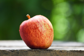 Fresh red apple on wooden table and nature green background