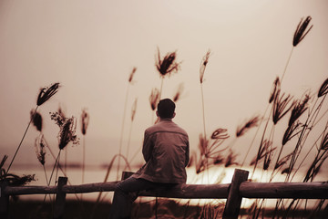 A lonely man sitting on the wooden with sunset
