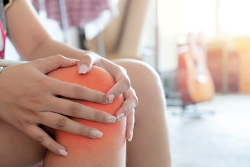 Woman having knee pain in home.