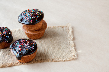 On the table fresh cupcakes drenched with chocolate and decorative sprinkles