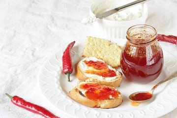 chili jam from chili pepper and paprika. fried toasts, soft (goat) cheese and chili jam. on a light background.