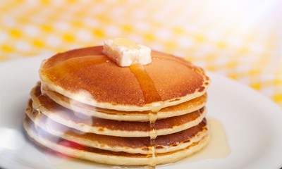 Stack of Small pancakes in syrup on background