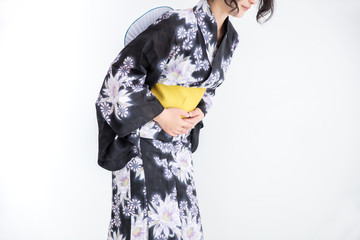 浴衣を着た30代のきれいな女性が白背景で腹痛でお腹を抱えている