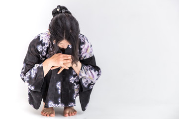 浴衣を着た30代のきれいな女性が白背景で体調くづしうづくまる