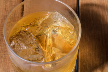 茶色い木目背景でロックグラスにウィスキーを注ぐ