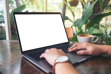 Mockup image of a woman using and typing on laptop with blank white desktop screen with coffee cup...