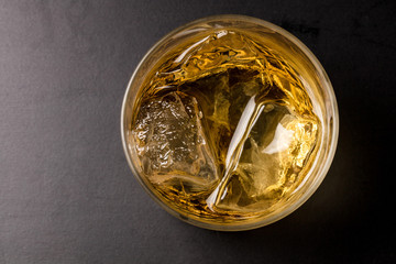 黒背景でロックグラスにウィスキーを注ぐ