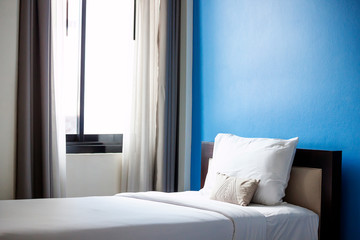 The clean white bed is located by the window to welcome the morning sun.