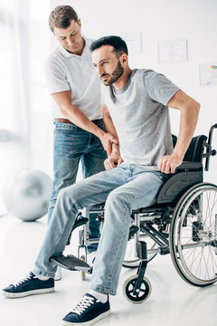Physiotherapist helping handicapped man in Wheelchair during recovery
