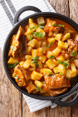 Homemade stew of short beef ribs with potatoes in a spicy sauce closeup in a pot. Vertical top view