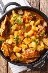 Beef ribs stewed with potatoes and gravy close-up in a pot. Vertical top view