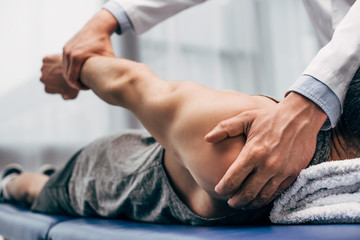 selective focus of chiropractor stretching arm of patient in hospital - obrazy, fototapety, plakaty
