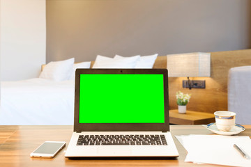 Fototapeta premium Laptop,smart phone and document on wooden table of defocused white pillow on bed decoration with light lamp in hotel bedroom interior background,Leisure and travel in the holiday concept.
