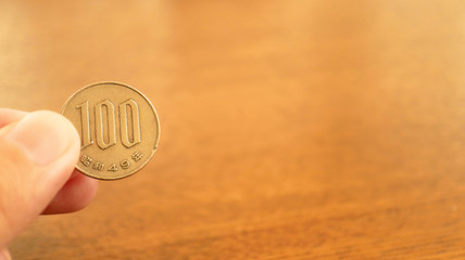 Close up the 100 Japanese Yen Coin on Finger