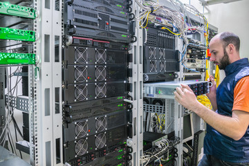 System administrator installs a new server in a modern data center. Engineer replaces the computer...