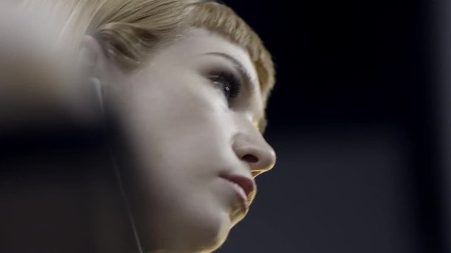 Close-up of young attractive woman listening to music with headphones. Action. Beautiful artistic young woman listening to music in small headphones and start dancing