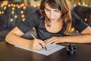 dream big set goals take action. Calligrapher Young Woman writes phrase on white paper. Inscribing...